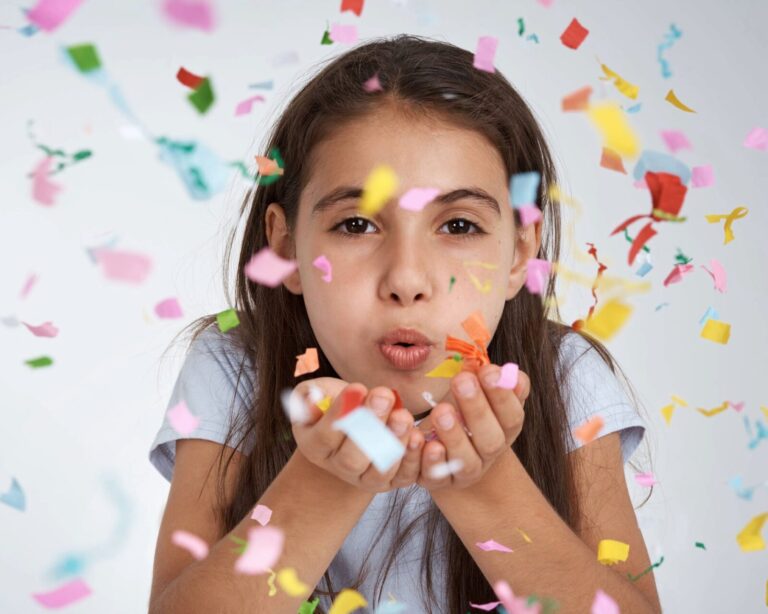 Visuel d'une jeune fille soufflant sur des confettis multicolore